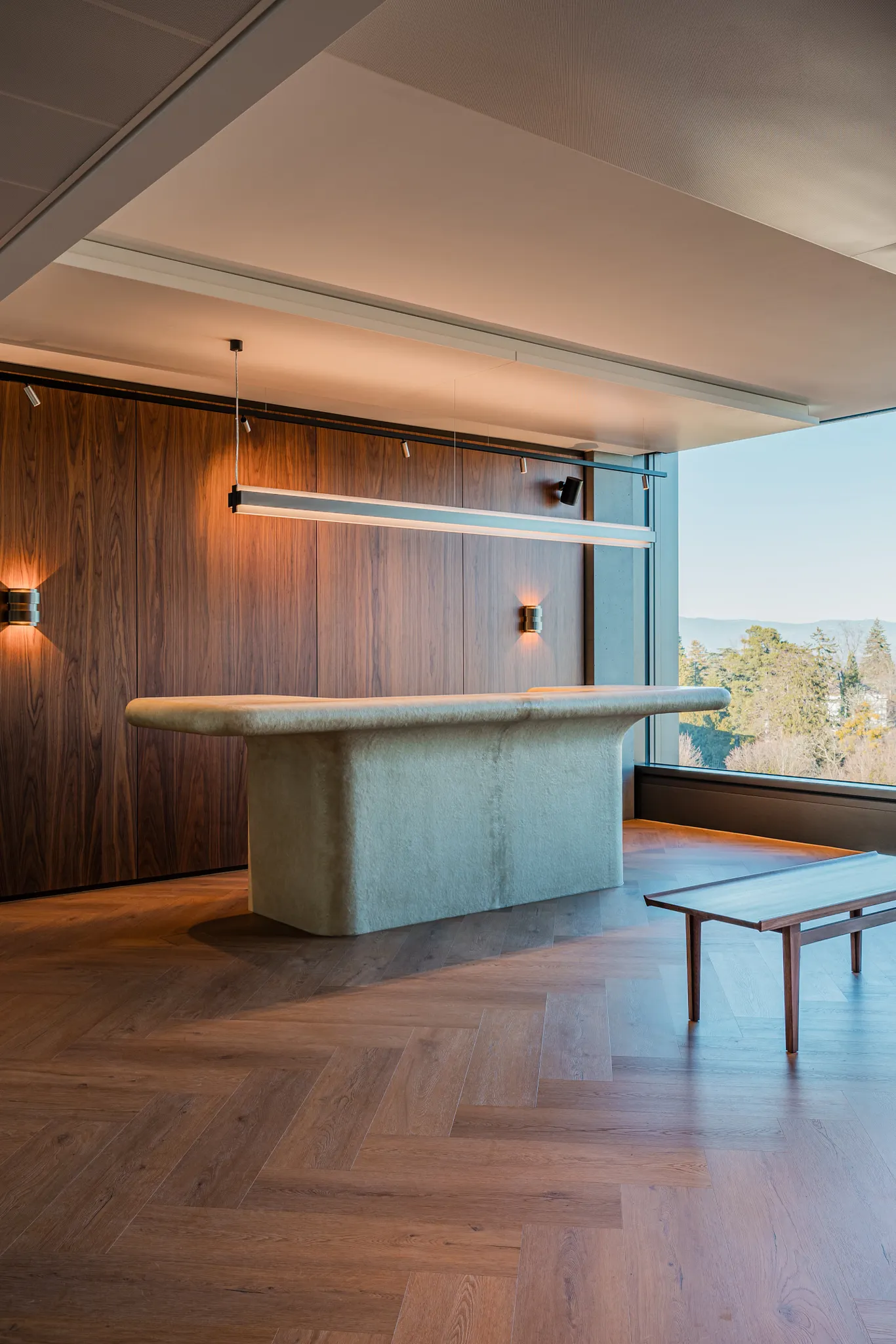 Modern reception desk with designer lighting, rich walnut storage room and rich wood herringbone floors