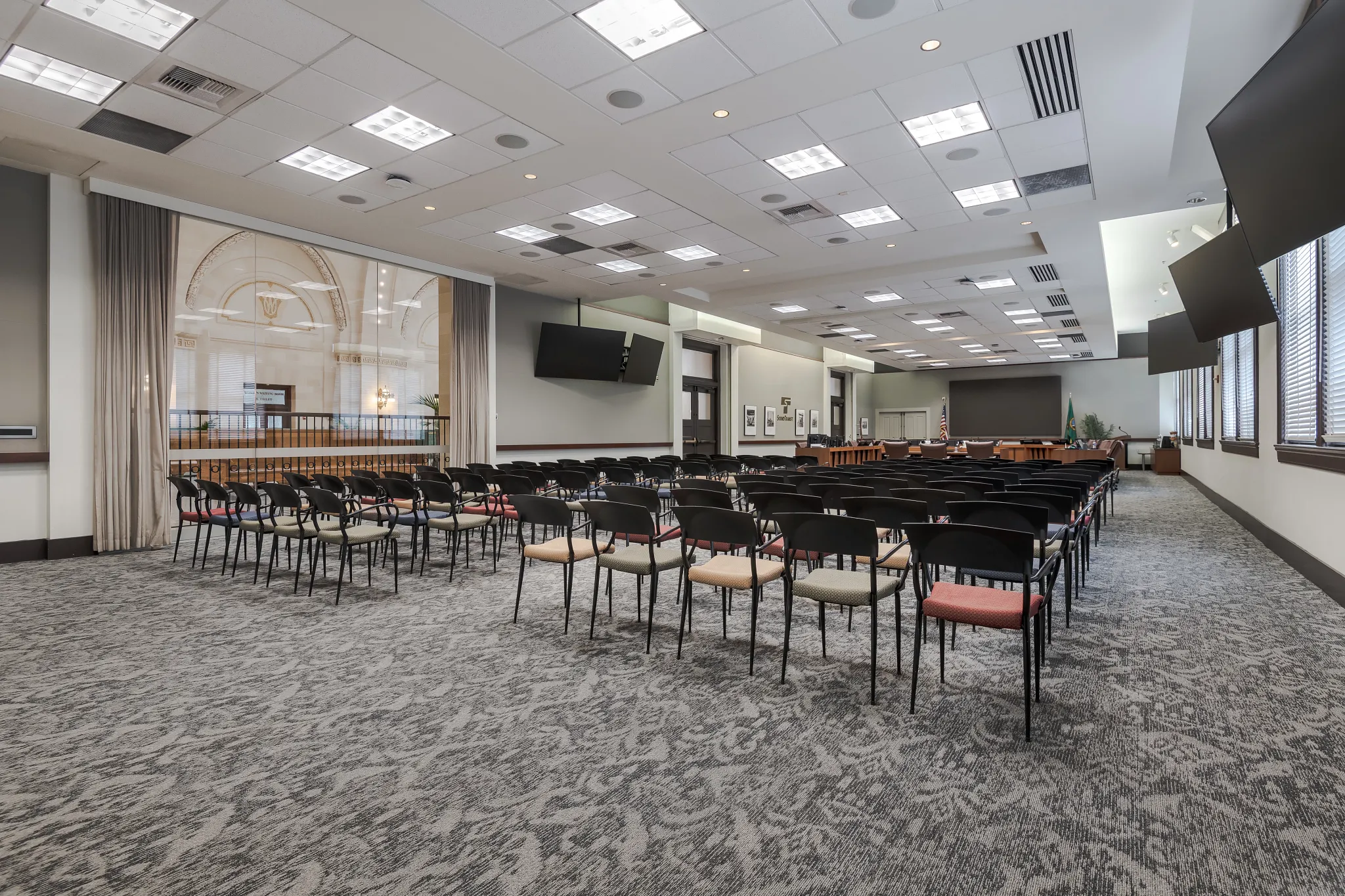 Conference room space with chairs, windows and carpet tile with abstract design  