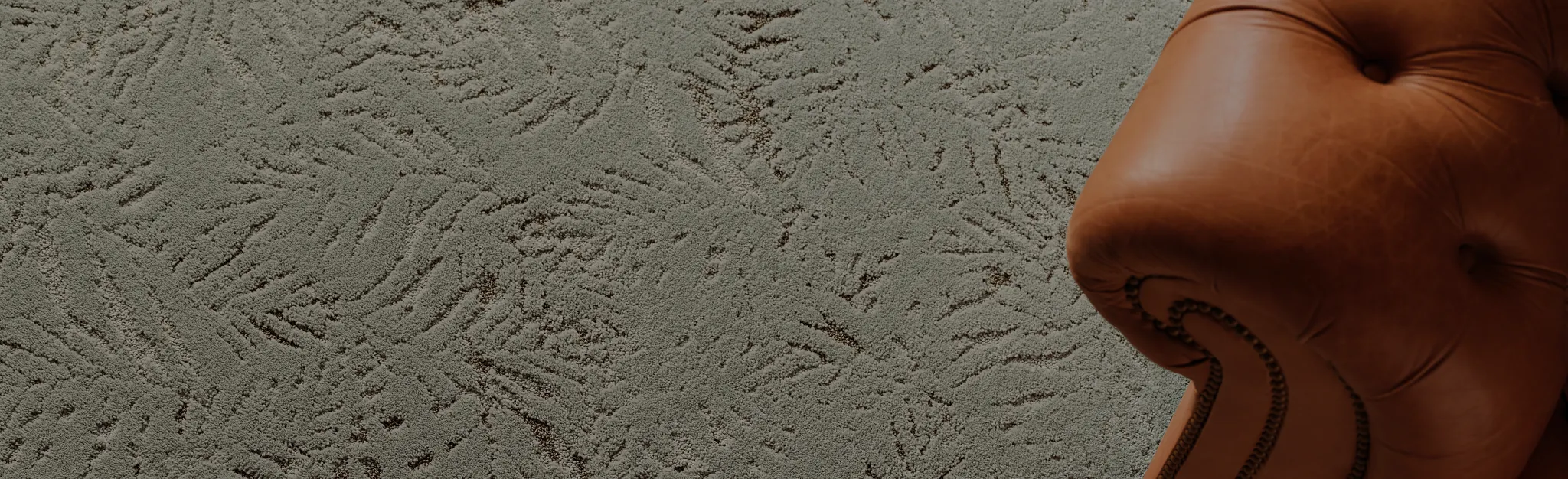 Dark gray carpet flooring with a textured pattern next to a wooden table with books and a plant