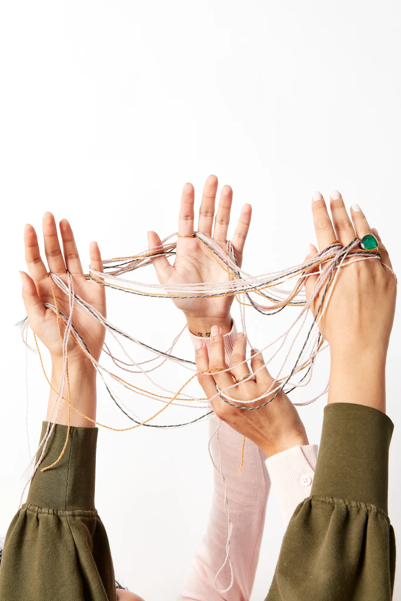 Hands of people intertwined with colorful threads against a white background