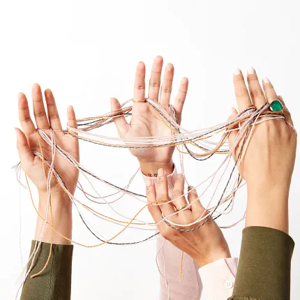 Collaborative teamwork concept with hands and threads in a workplace setting Hands of people intertwined with colorful threads against a white background