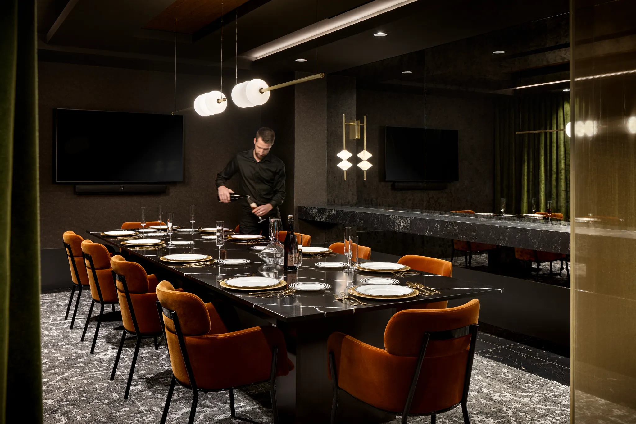 Elegant dining room with modern lighting and orange chairs on a textured carpet floor