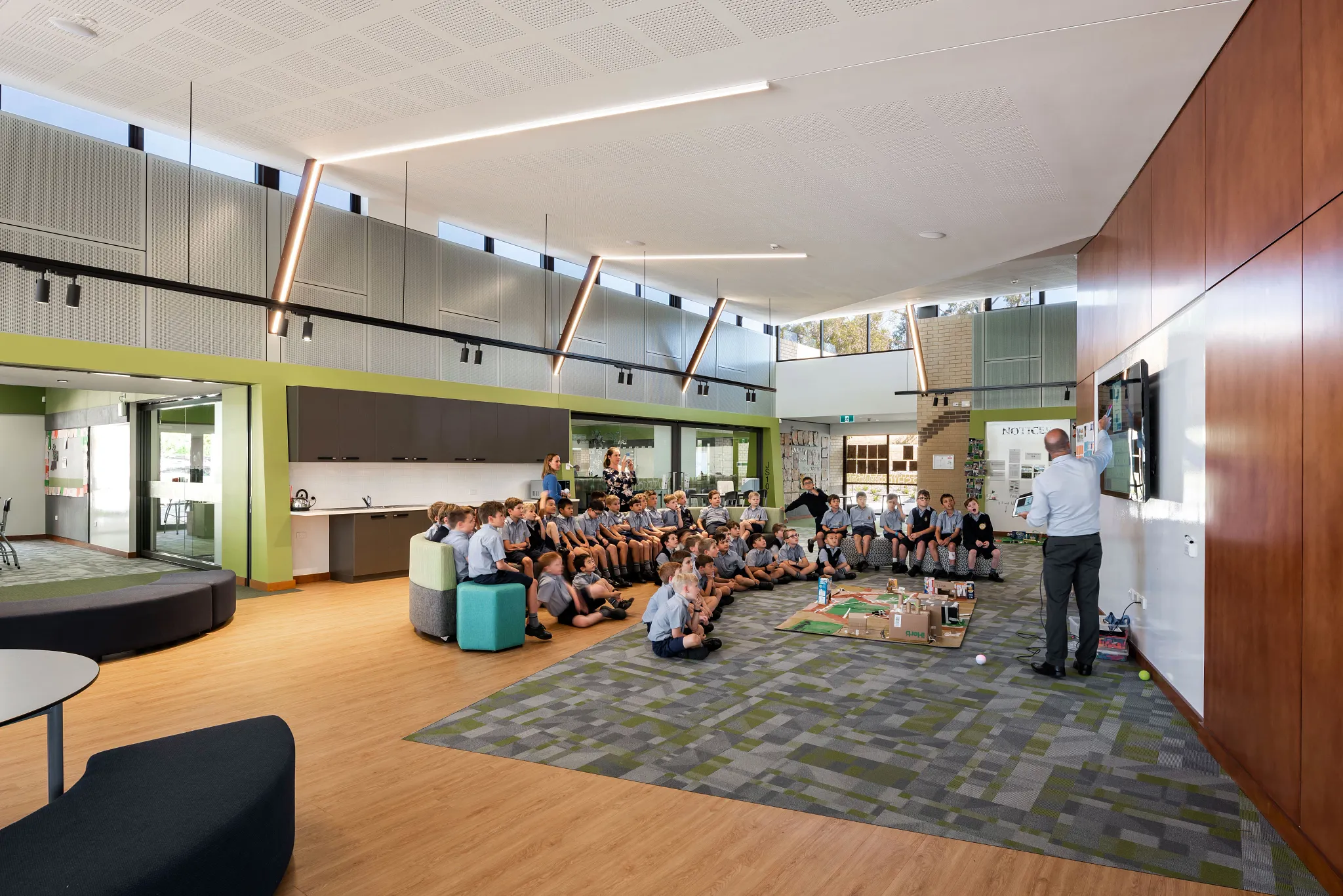 Education facility with students seated on patterned carpet tiles and wood-look flooring