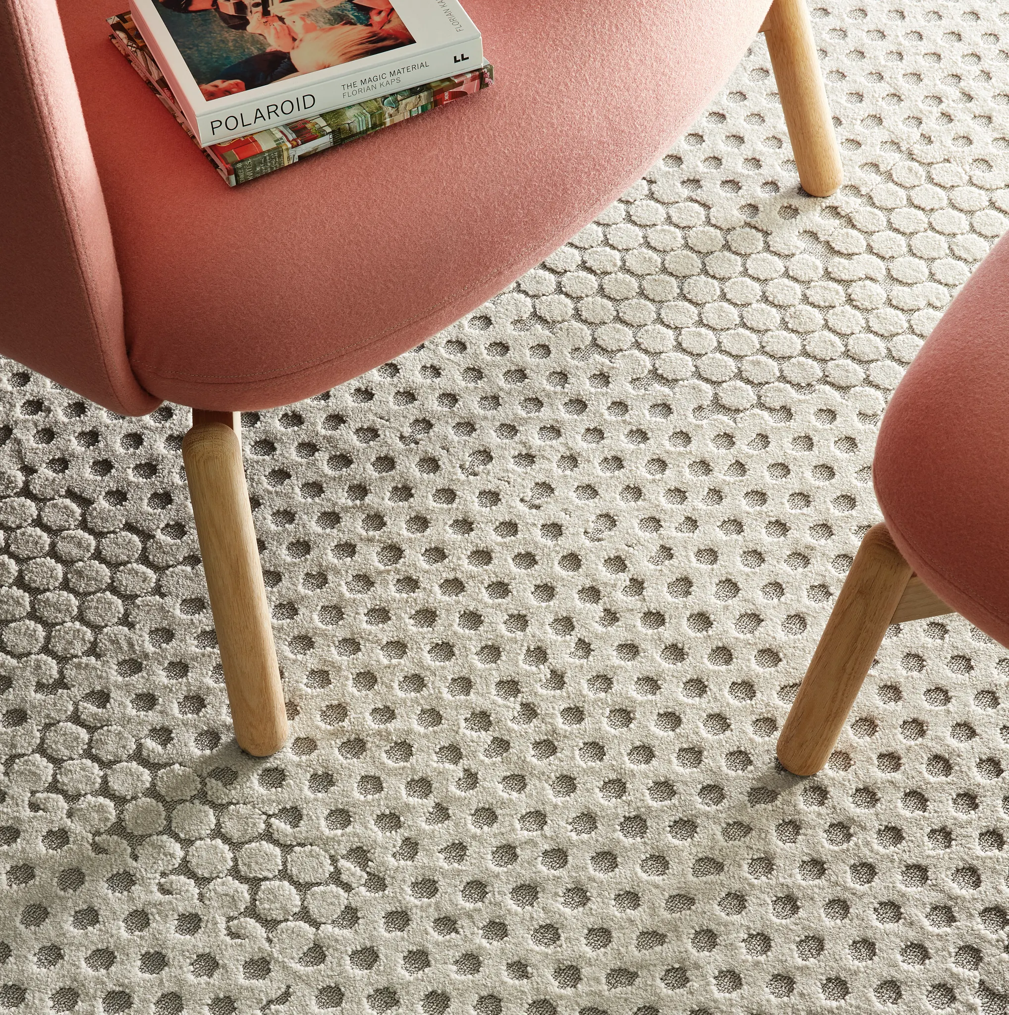 Modern seating area with pink chairs on textured beige carpet