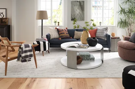 Contemporary living room with light wood flooring and stylish decor Modern living room with light wood flooring, featuring a navy sofa, colorful cushions, and a white round coffee table