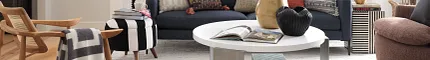Contemporary living room with light wood flooring and stylish decor Modern living room with light wood flooring, featuring a navy sofa, colorful cushions, and a white round coffee table
