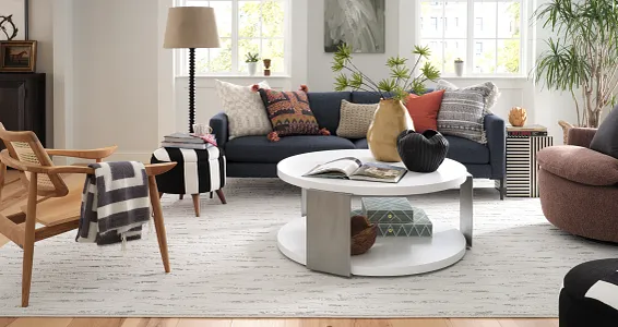 Contemporary living room with light wood flooring and stylish decor Modern living room with light wood flooring, featuring a navy sofa, colorful cushions, and a white round coffee table