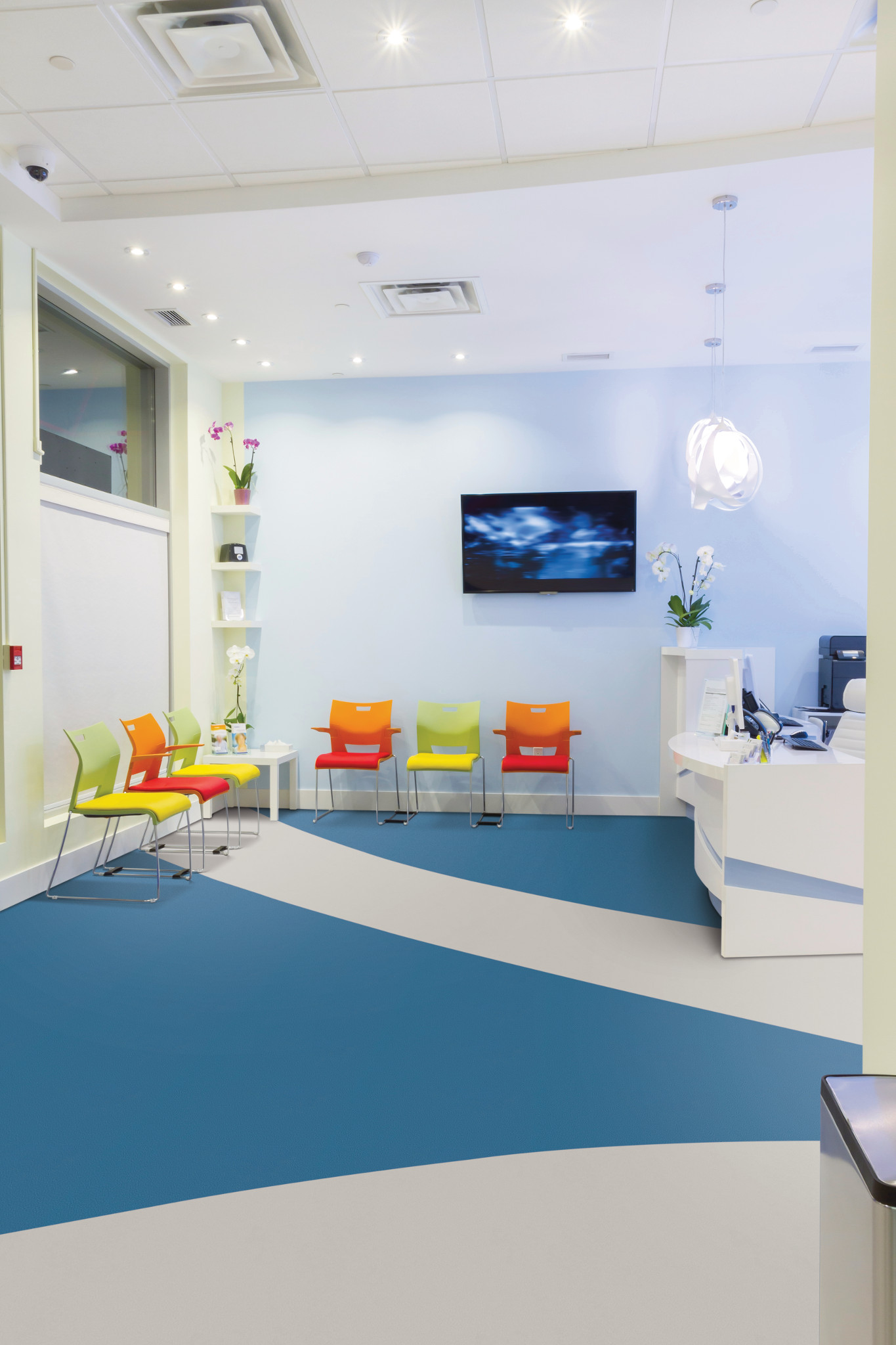 
  "Modern waiting room with colorful chairs and blue and gray luxury vinyl flooring"
)