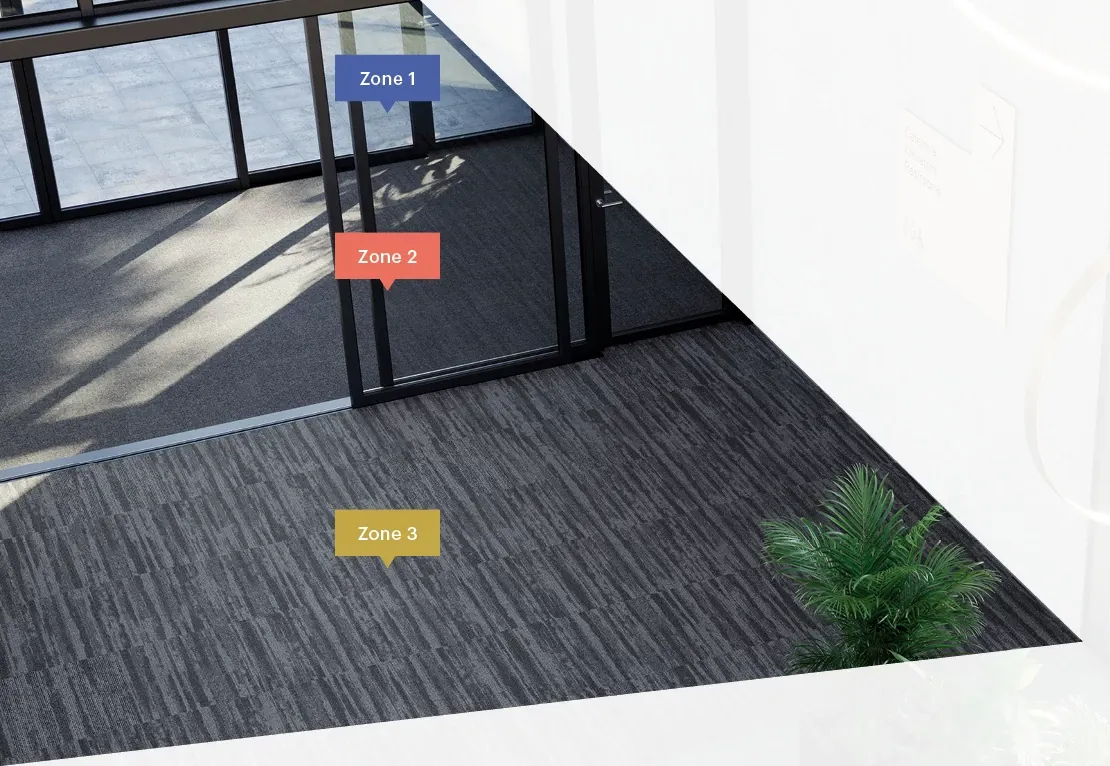 Modern commercial carpet tile flooring in a spacious, well-lit workplace environment with distinct zones marked by color-coded labels