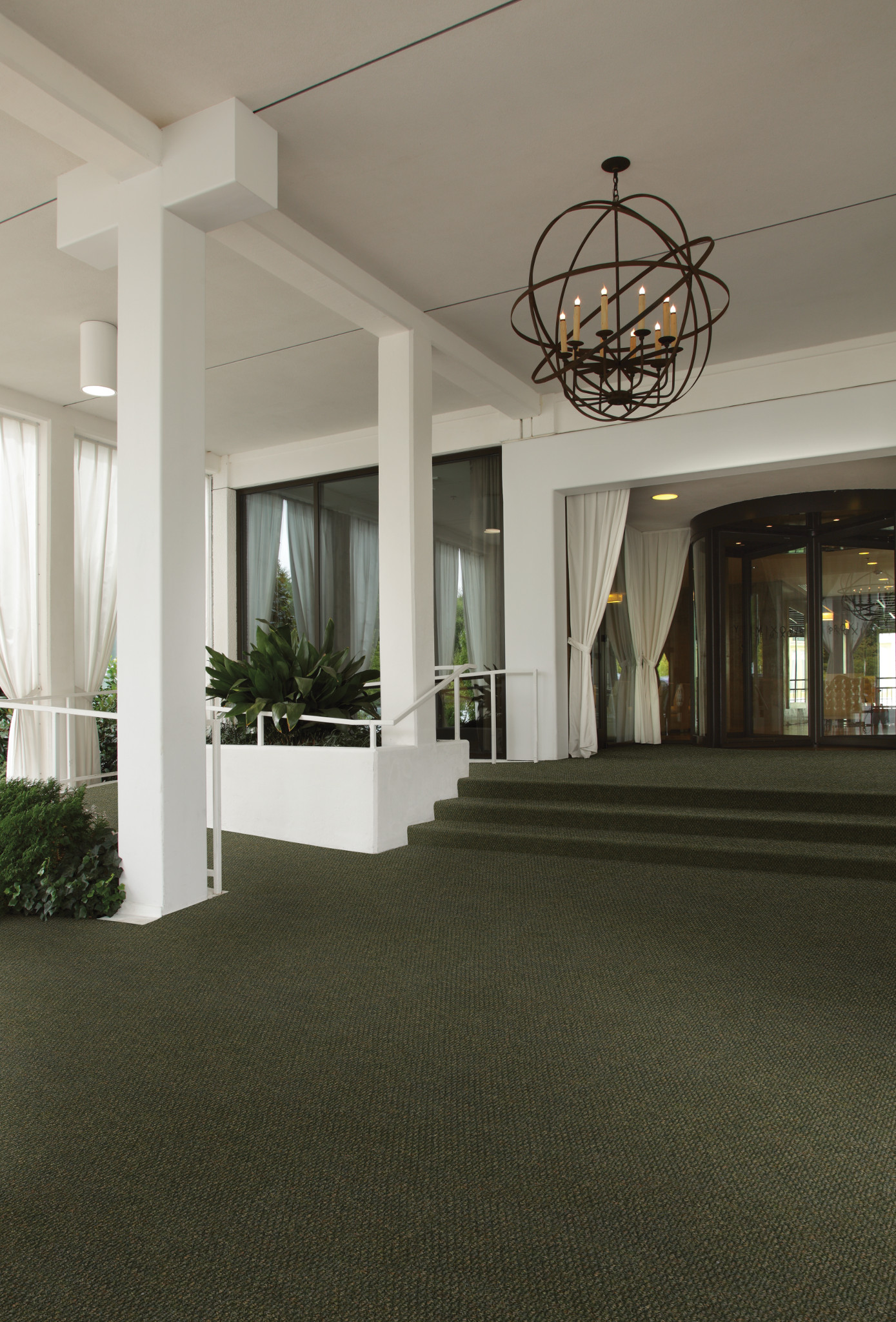 
  "Elegant commercial space with green carpet flooring, white pillars, and modern chandelier"
)