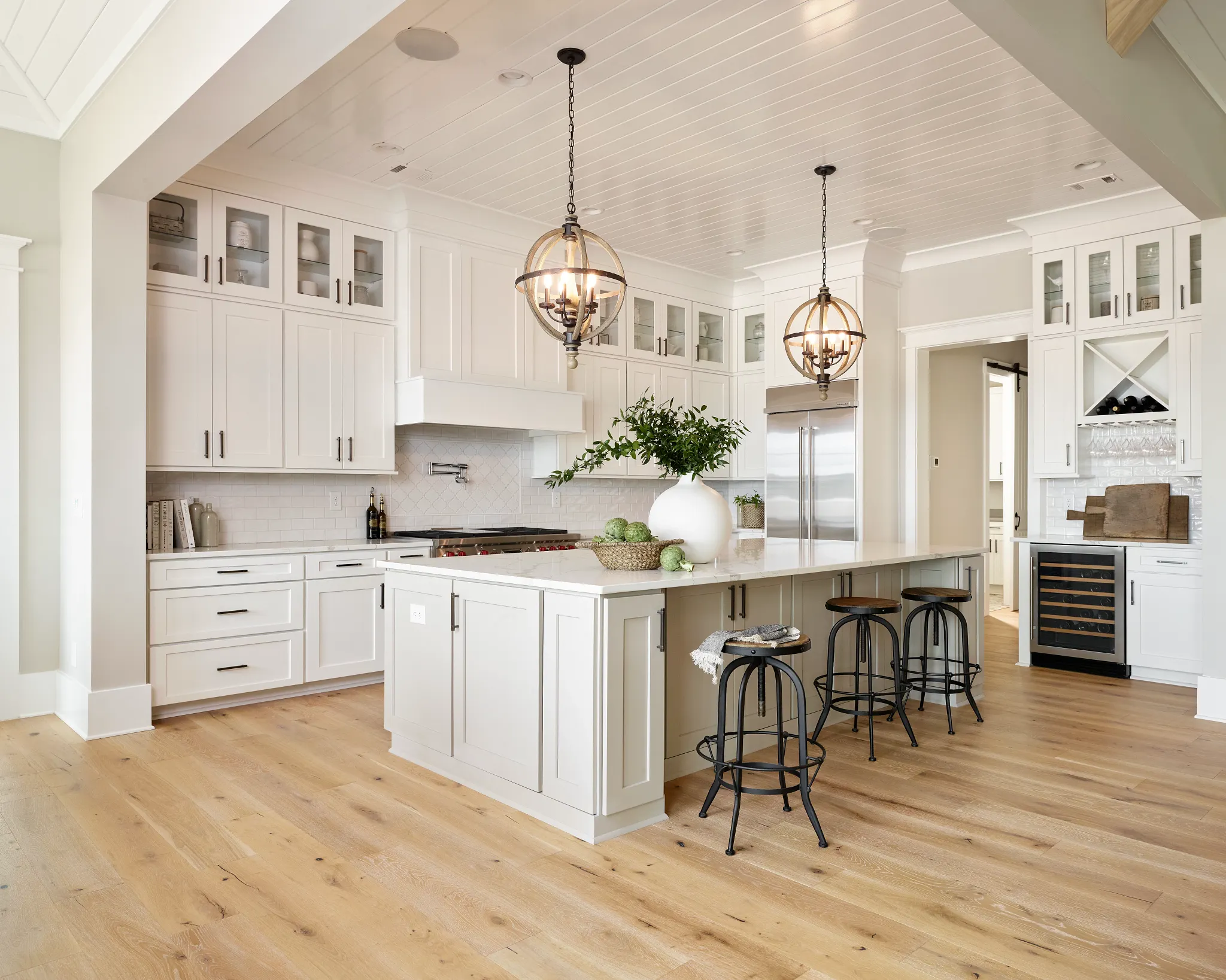 Modern kitchen with light hardwood flooring, white cabinetry, and pendant lighting for a warm and inviting atmosphere