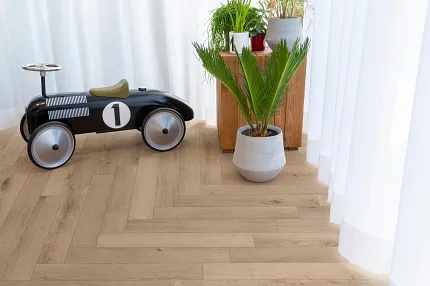 Light Oak Wood Look Luxury Vinyl Plank Flooring in Modern Living Room Scene Modern living room with light oak wood look luxury vinyl plank flooring, featuring a black toy car and potted plants near sheer curtains