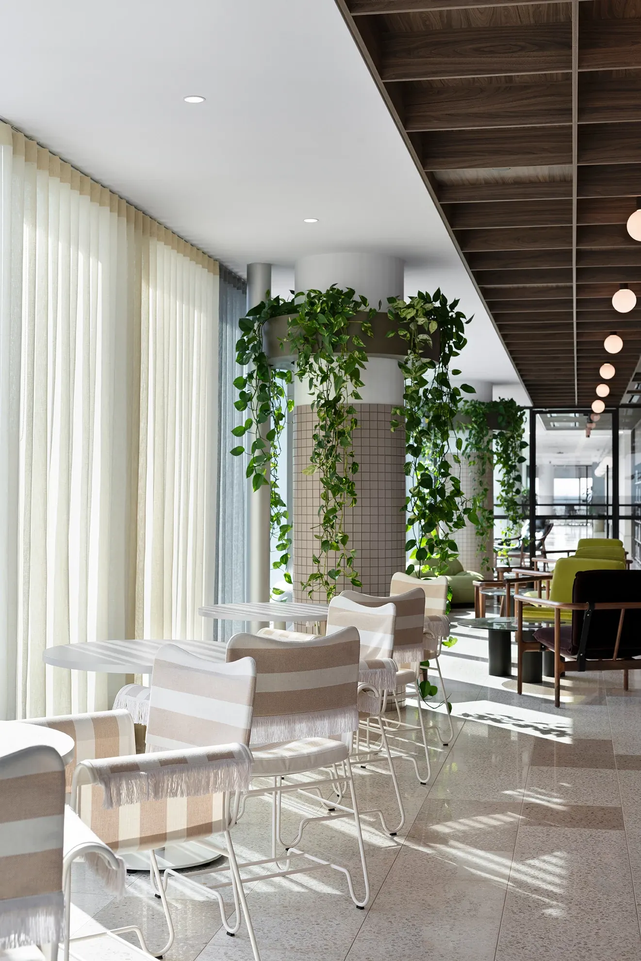 Modern hospitality facility with terrazzo flooring, white and beige striped chairs, and lush green plants