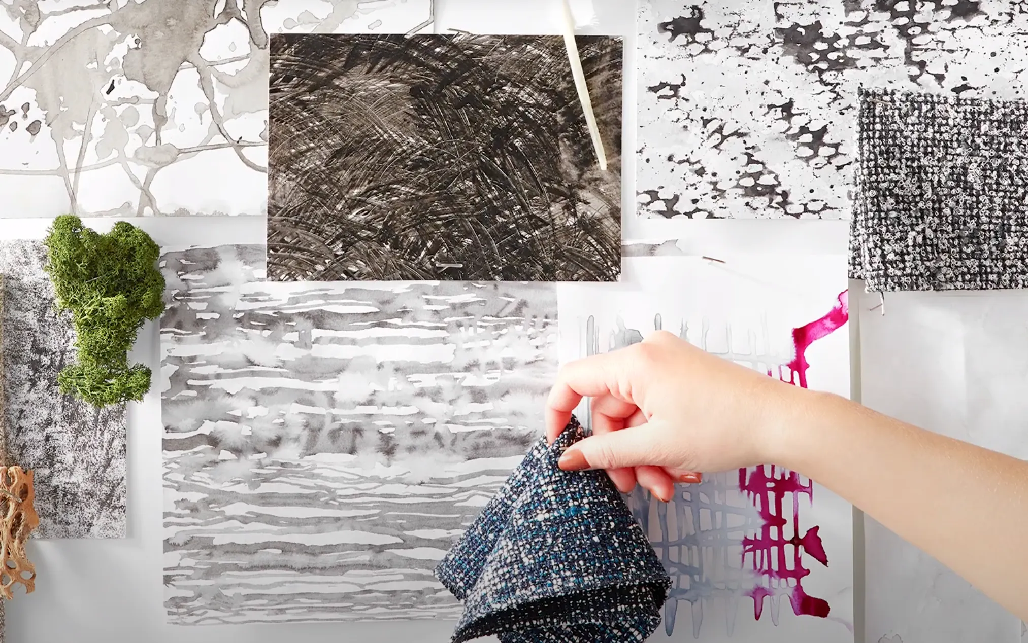 Hand holding blue and black textured fabric swatches over abstract black and white art designs