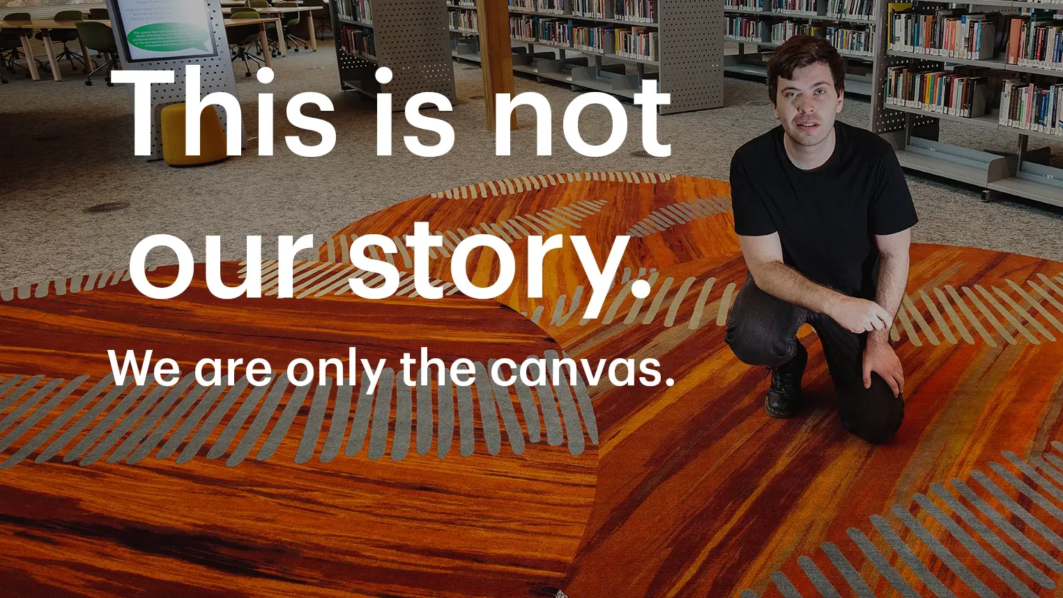 Man in library with 3 bright orange rugs