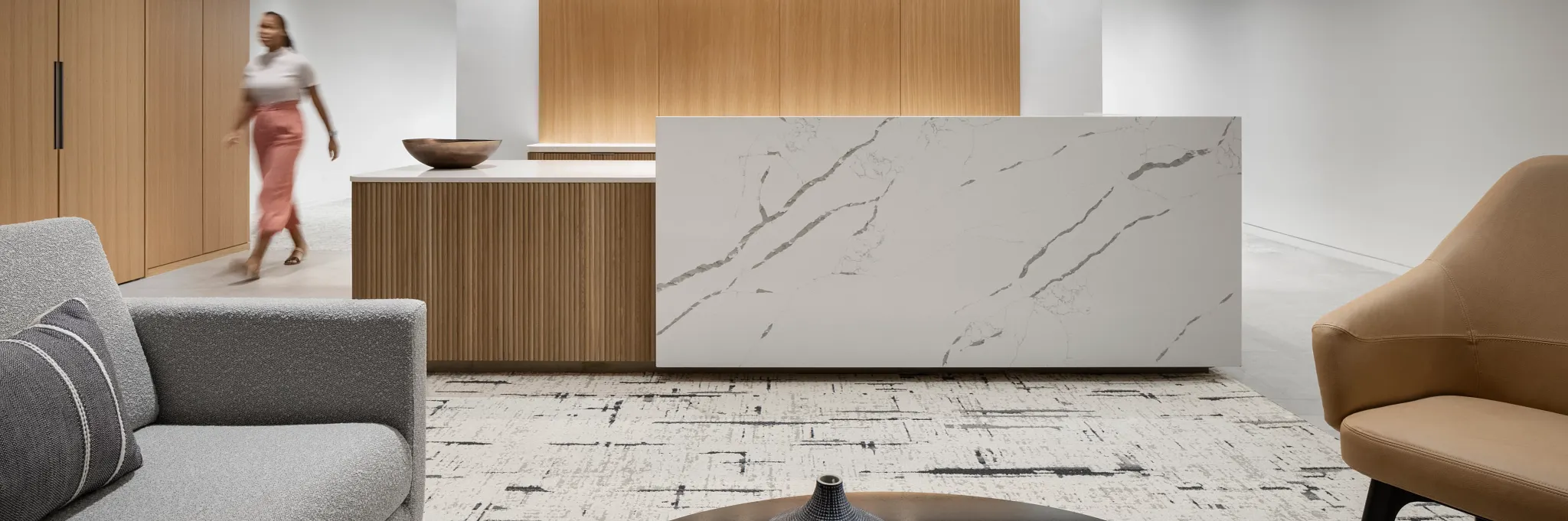 Modern workplace interior with a marble reception desk, wooden paneling, and contemporary furniture