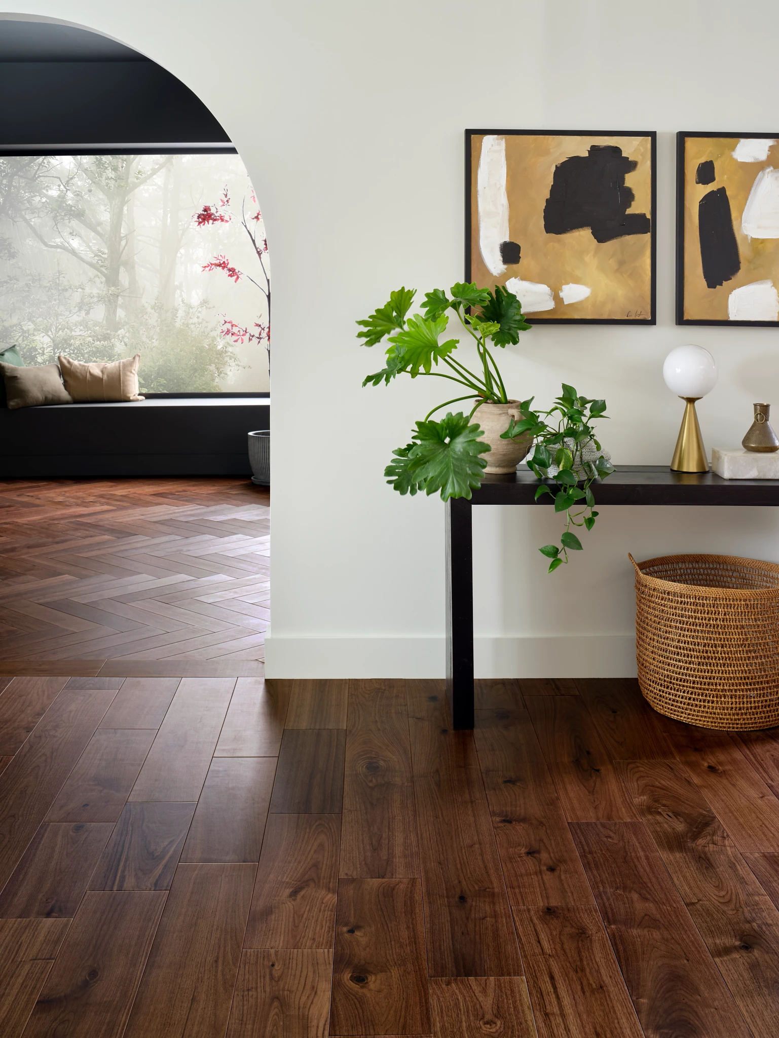living room with rich brown hardwood floor with a console table with plants and abstract art on the wall