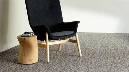 Contemporary lounge with commercial carpet tile flooring Modern lounge area with a black chair and wooden side table on patterned commercial carpet tile