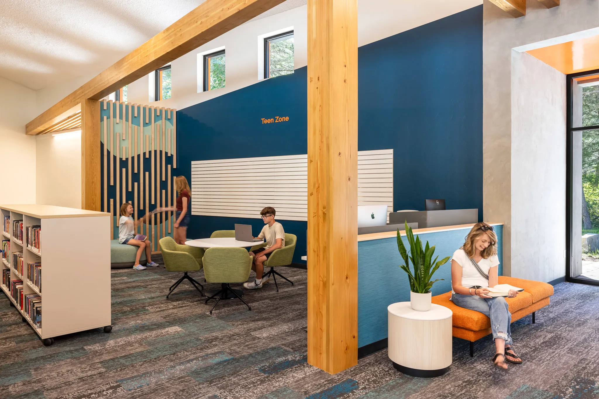 Modern education facility with students in a library setting featuring commercial carpet tile flooring in shades of blue and gray