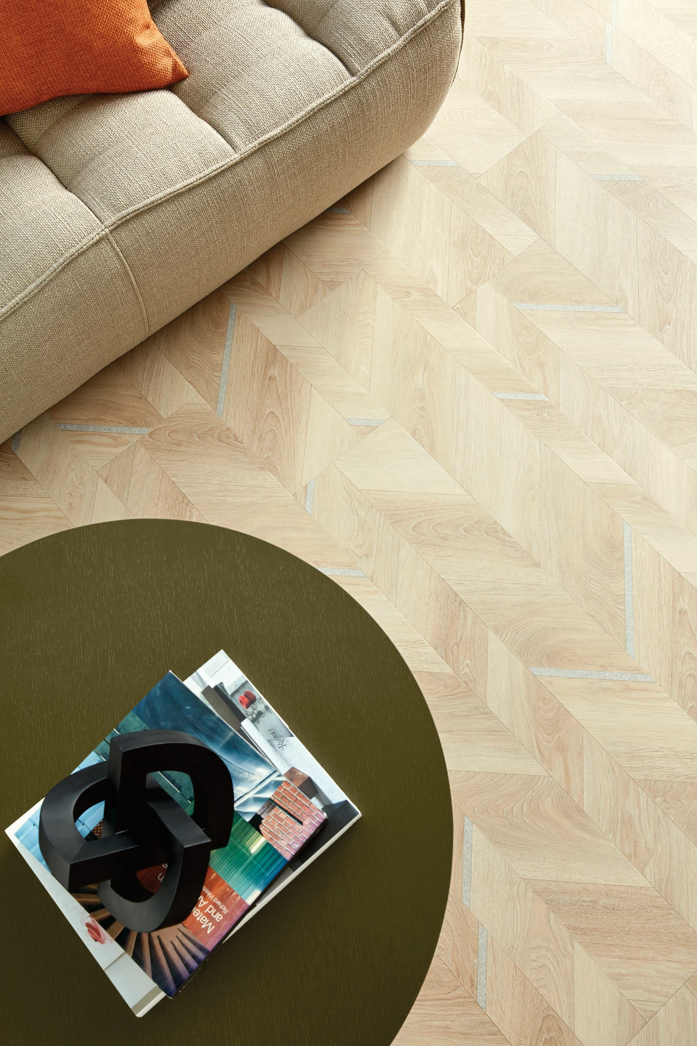 Light wood patterned flooring in a modern living room with a beige sofa and a round green table
