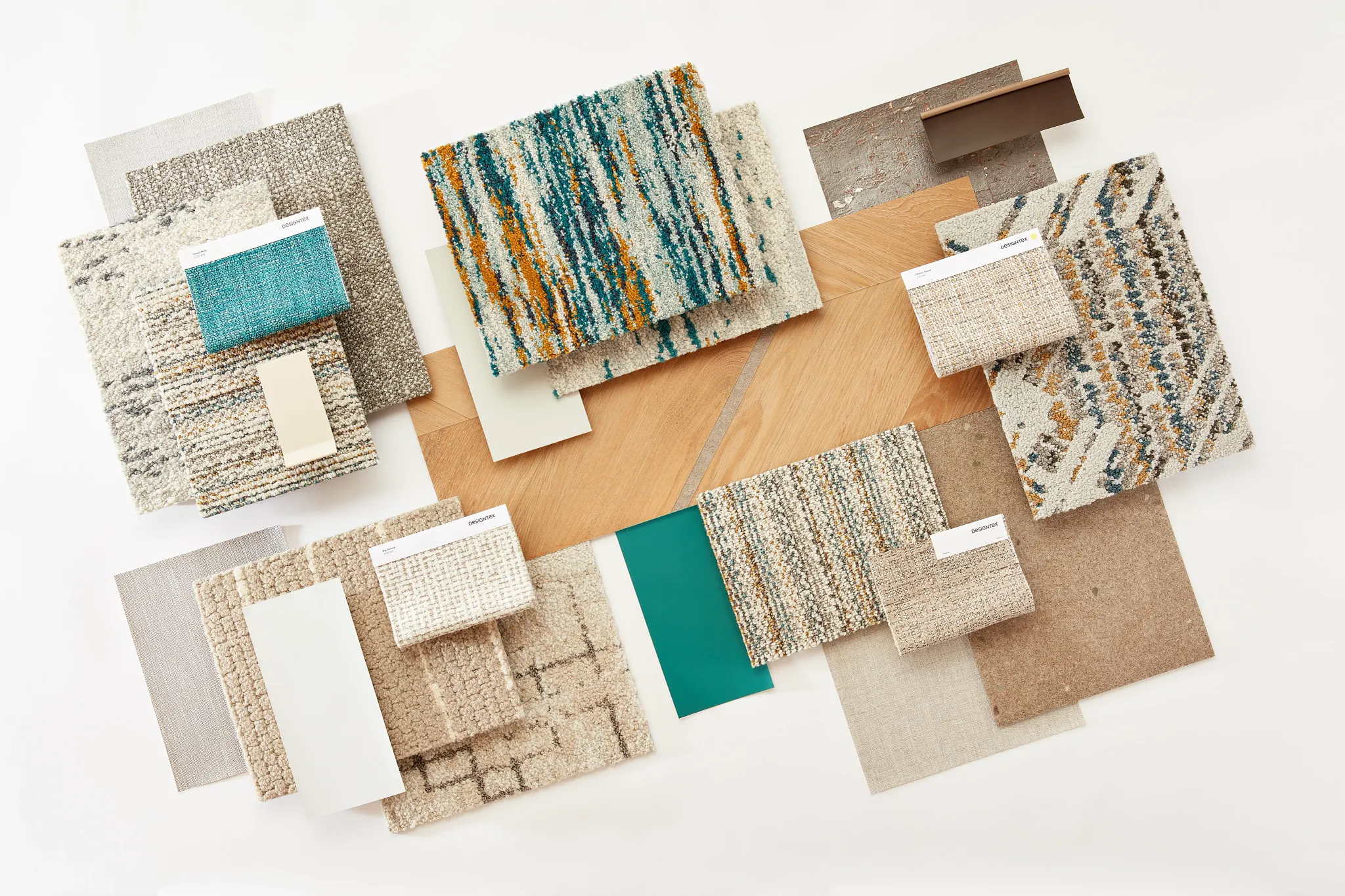 Assorted flooring swatches including commercial carpet tiles in beige, teal, and multicolor patterns, with wood and tile samples