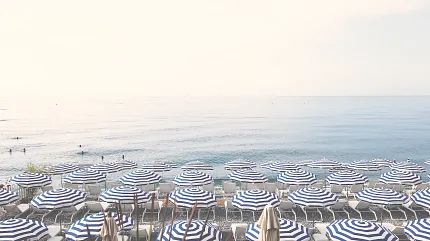 Serene beach view with striped umbrellas and ocean backdrop Beach scene with blue and white striped umbrellas and calm sea