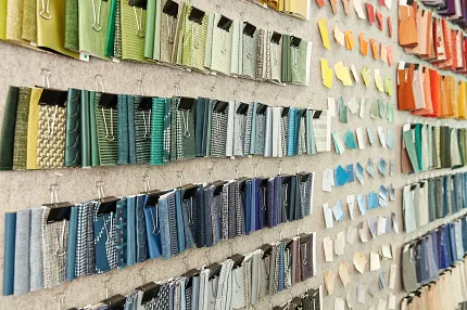 Colorful Fabric Swatch Display for Interior Design Inspiration Colorful fabric swatches displayed on a wall, showcasing a variety of textures and patterns in shades of green, blue, yellow, orange, and red.