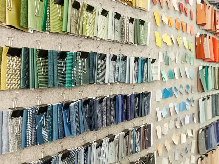 Colorful Fabric Swatch Display for Interior Design Inspiration Colorful fabric swatches displayed on a wall, showcasing a variety of textures and patterns in shades of green, blue, yellow, orange, and red.