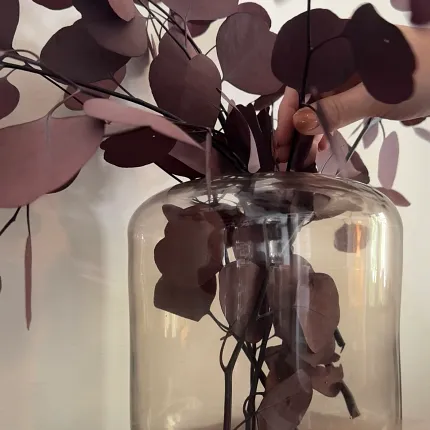 Burgundy Leaf Arrangement in Glass Vase on Wooden Table Decorative vase with burgundy leaves on a wooden surface