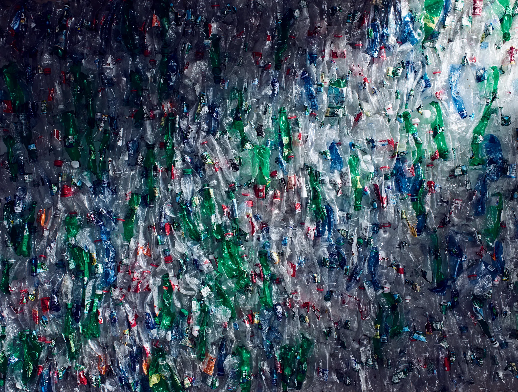 Recycled plastic bottles in various colors including green, blue, and clear