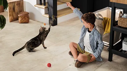 Beige Stone Look Luxury Vinyl Tile Flooring - 24x12 inch SPC Construction Young boy playing with a cat on beige stone look luxury vinyl tile flooring
