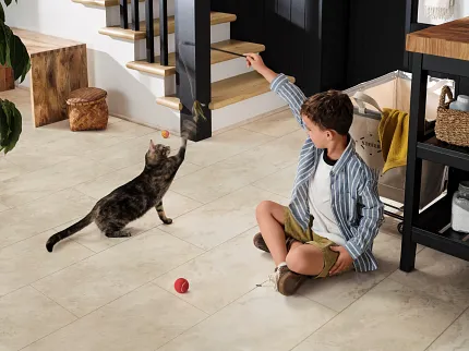 Beige Stone Look Luxury Vinyl Tile Flooring - 24x12 inch SPC Construction Young boy playing with a cat on beige stone look luxury vinyl tile flooring