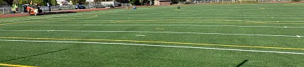 Artificial Turf Football Field Scene Artificial turf football field with clear blue sky and surrounding trees