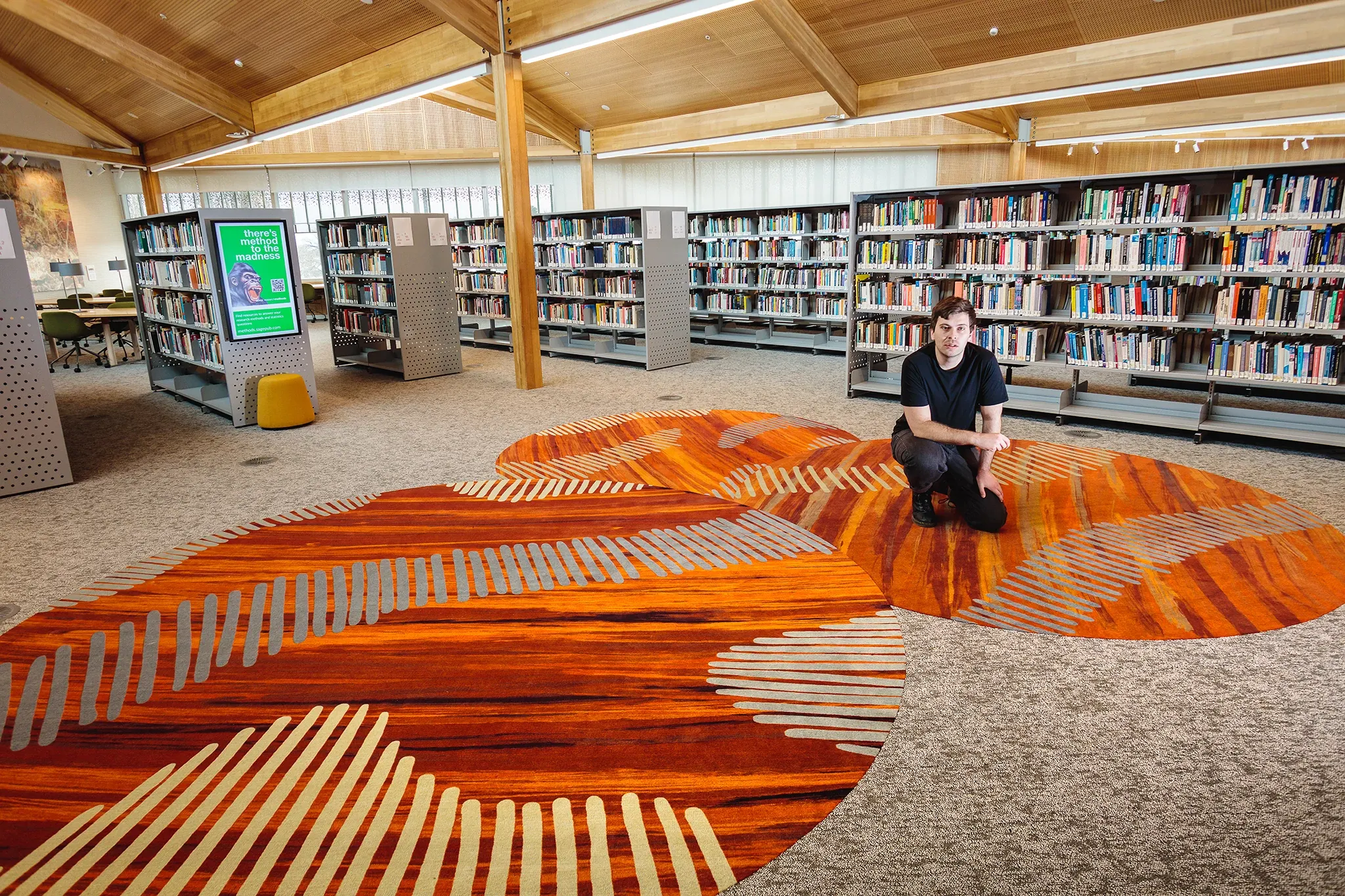 Custom carpet flooring inspired by Indigenous artwork installed within the University of Tasmania library, shown alongside the collaborating artist.