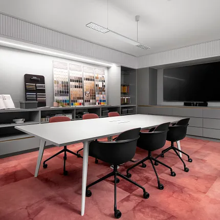 Colorful Carpet Swatches Display in Modern Showroom Modern showroom with a variety of colorful carpet swatches displayed on a wooden wall, featuring a mix of blue, green, orange, pink, and gray tones, with industrial lighting and shelving in the background