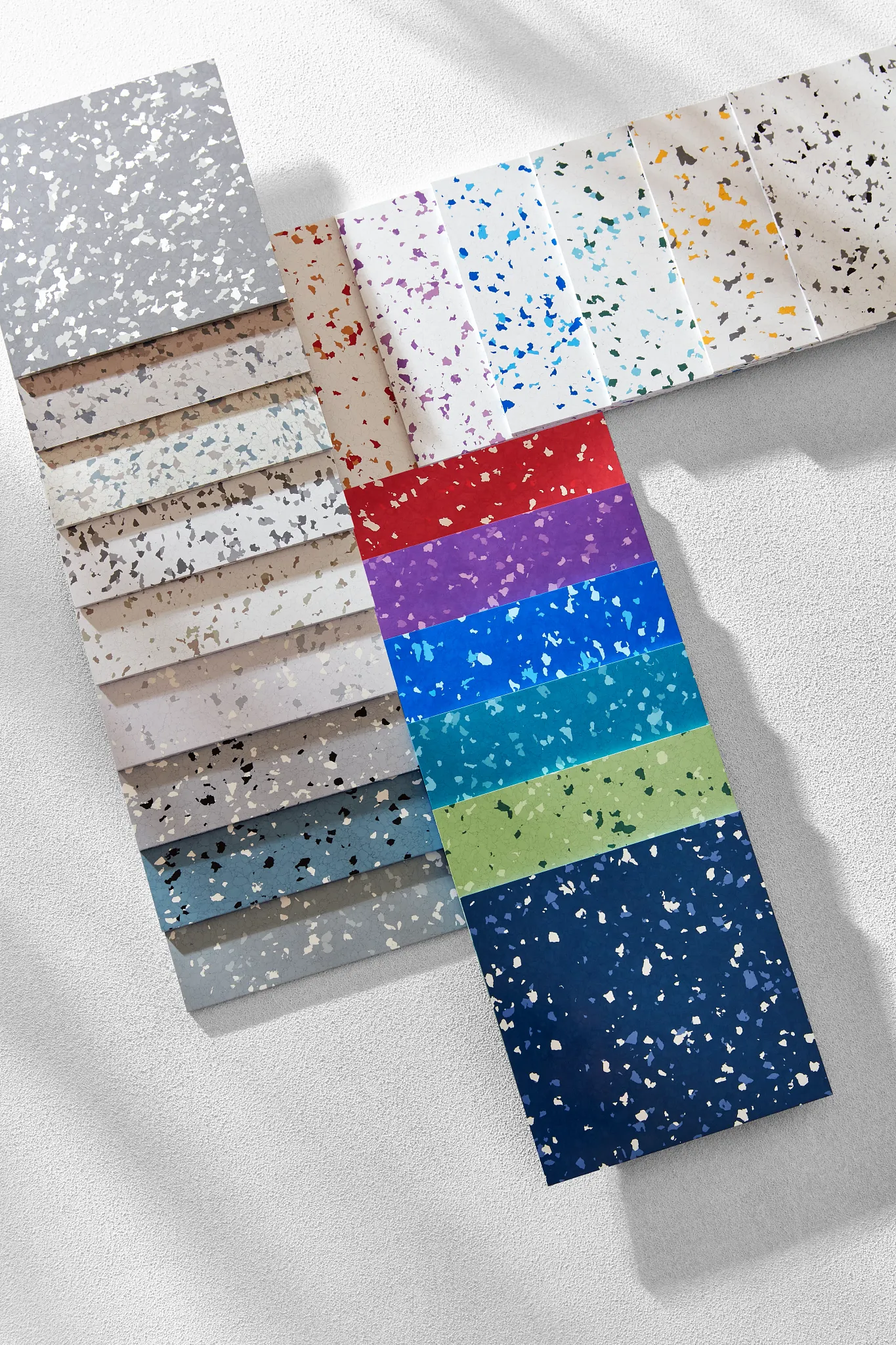 Swatch of commercial heterogeneous sheet vinyl flooring in various colors including grey, beige, red, purple, blue, green, and navy