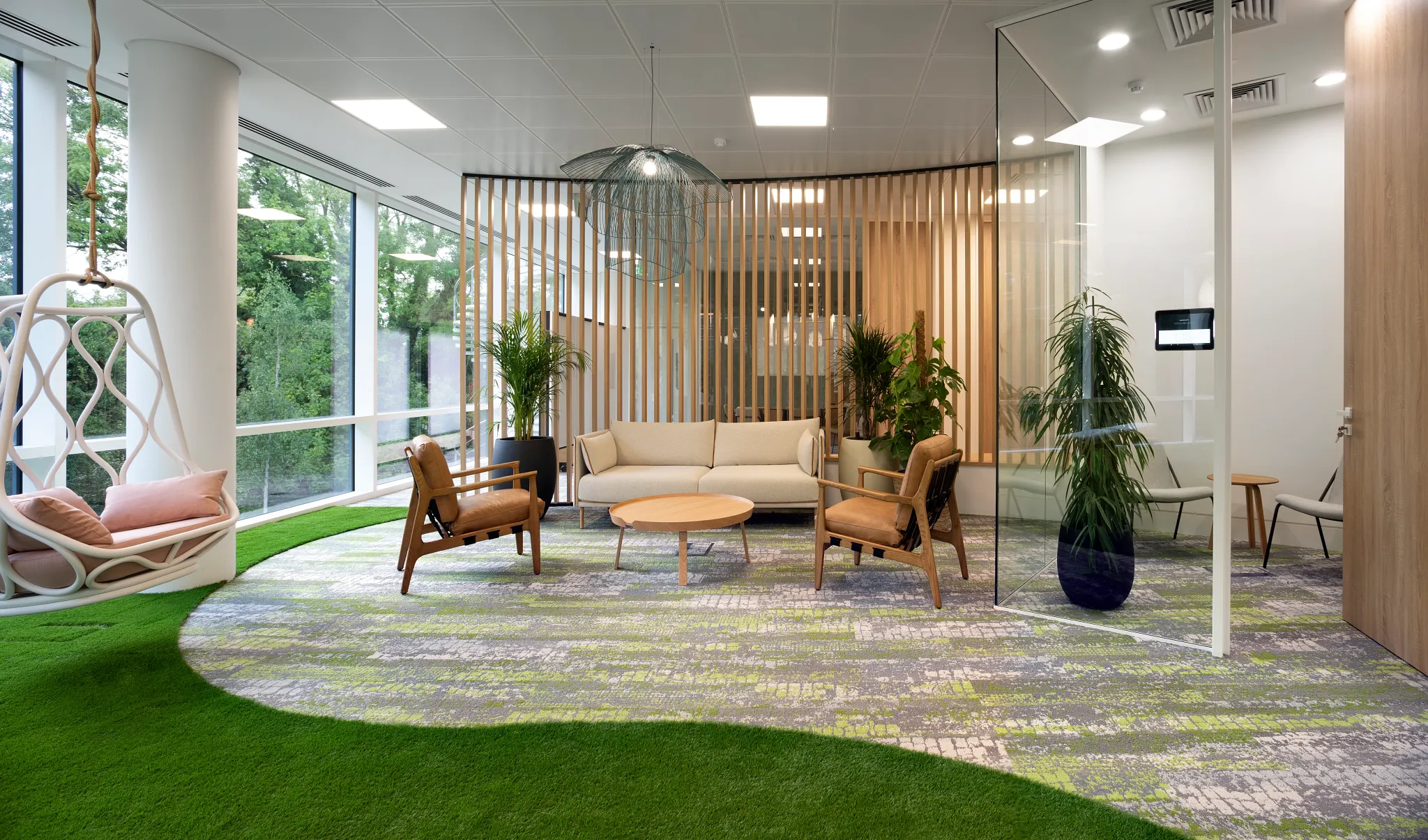 Modern workplace lounge area with green and gray commercial carpet tile, featuring contemporary furniture and large windows