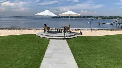 Relaxing waterfront patio with green lawn and seating Scenic outdoor patio with umbrellas by the waterfront