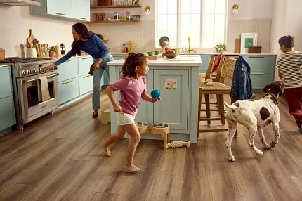 Preferred Flooring of American Kennel Club A golden retriever walks into a brightly lit room on a leash, trotting on Pet Perfect carpet from Shaw Floors. The image includes a graphic that reads "Preferred Flooring of American Kennel Club"