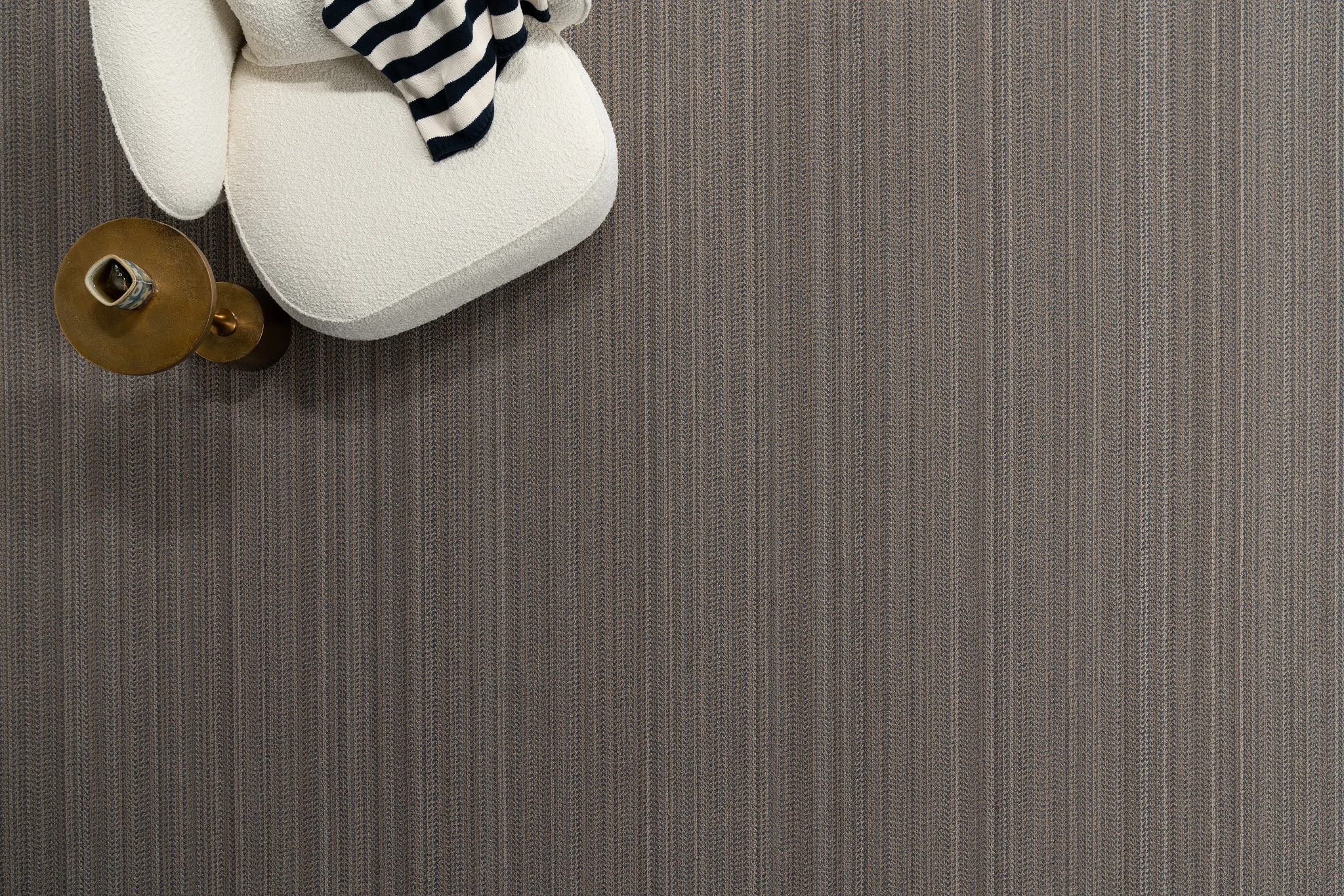 Striped gray carpet flooring with a modern white chair and striped cushion