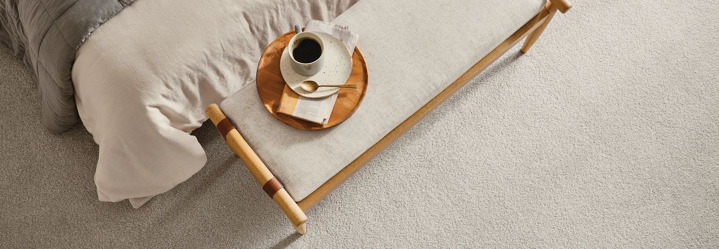 bed with table and coffee on carpet with tonal visuals