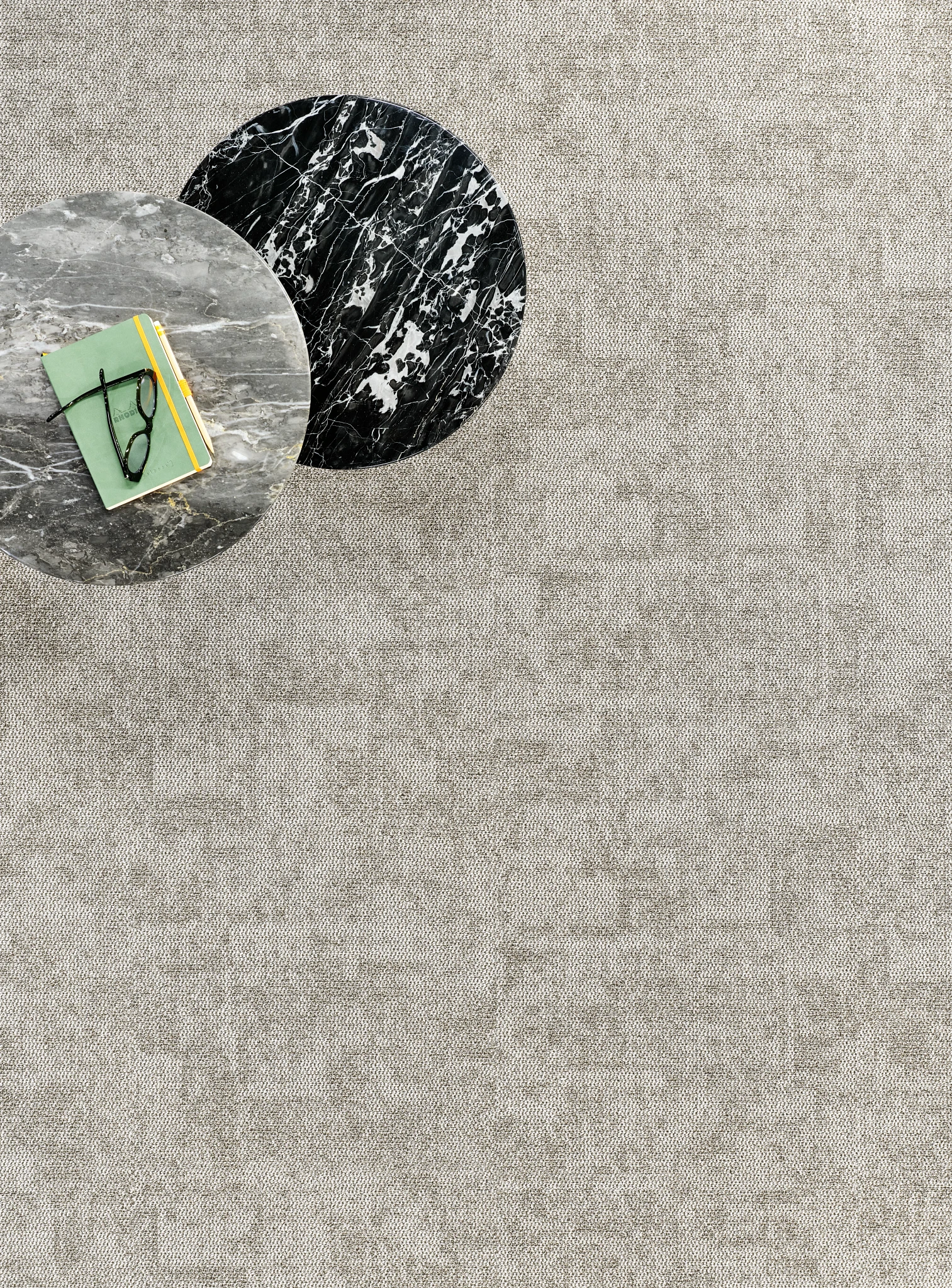 Beige textured commercial carpet tile with marble tables and a book with glasses on top