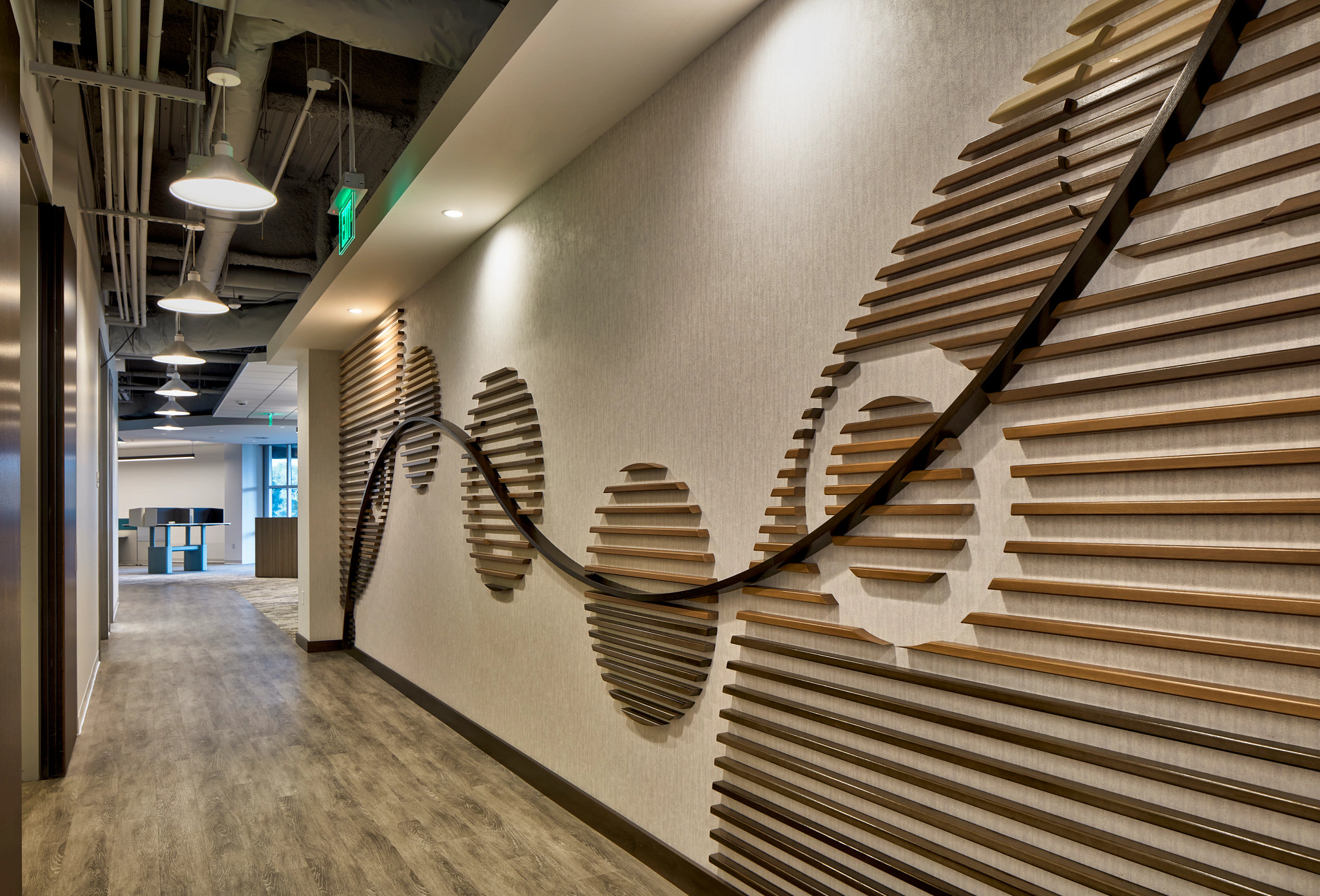 Modern workplace hallway with heavy commercial luxury vinyl tile flooring, featuring a unique wall design and exposed ceiling, 48x6 inch LVT flooring in a workplace setting.