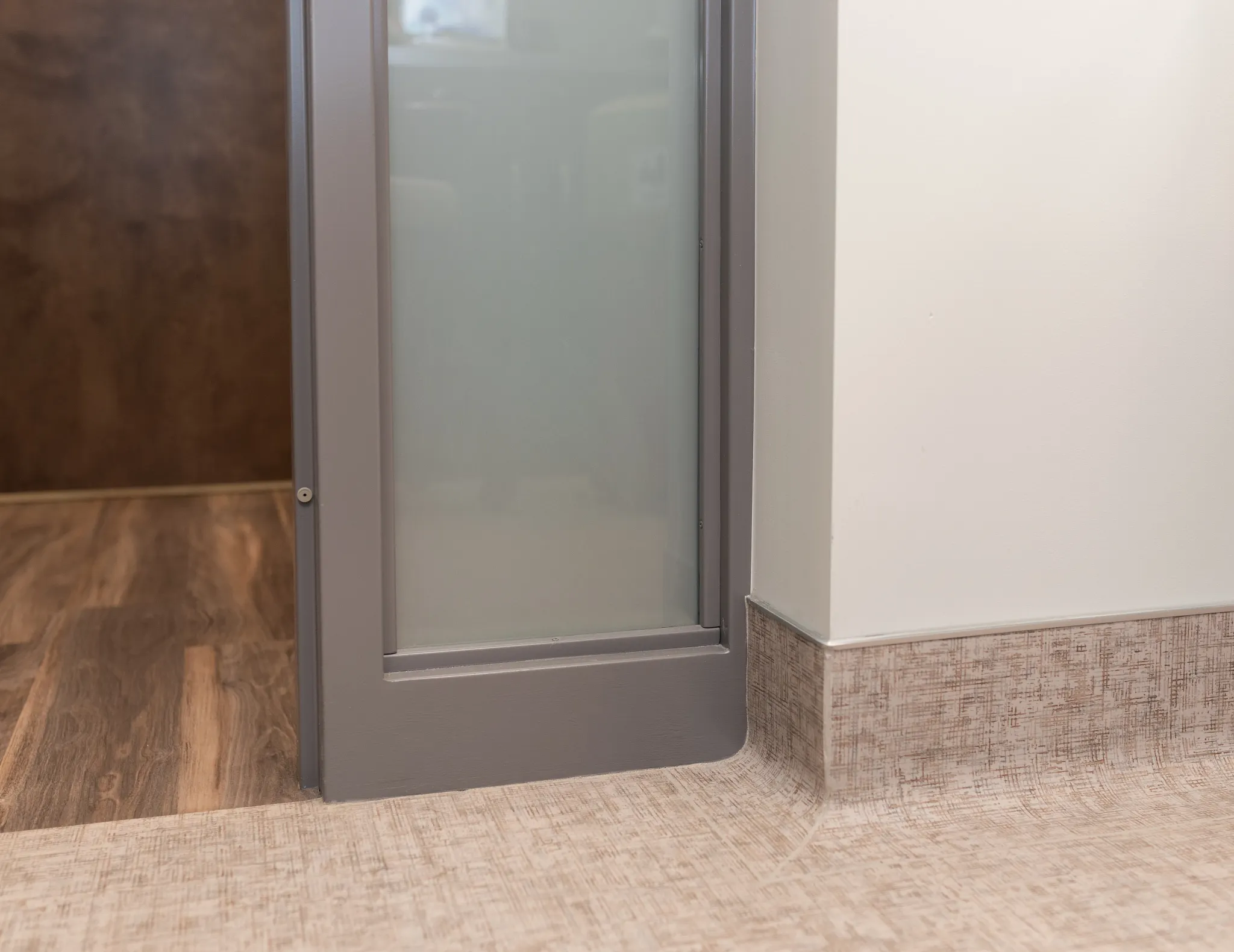 Modern room scene with wood-look hard surface flooring and beige textured baseboard