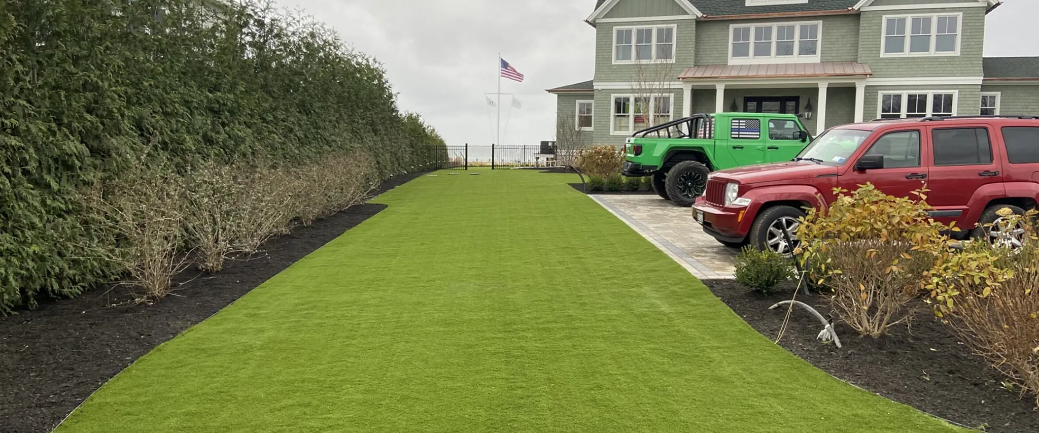 Green artificial grass lawn in front of a suburban house