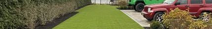 Green artificial grass lawn in front of a suburban house
