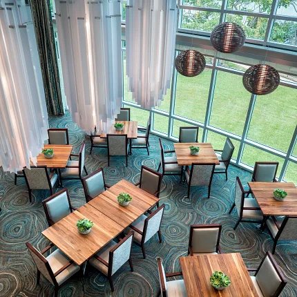 Senior Living Dining Area with Modern Decor and Commercial Carpet Tile Flooring Aerial view of a senior living dining area with modern wooden tables, cushioned chairs, and intricate patterned commercial carpet tile flooring