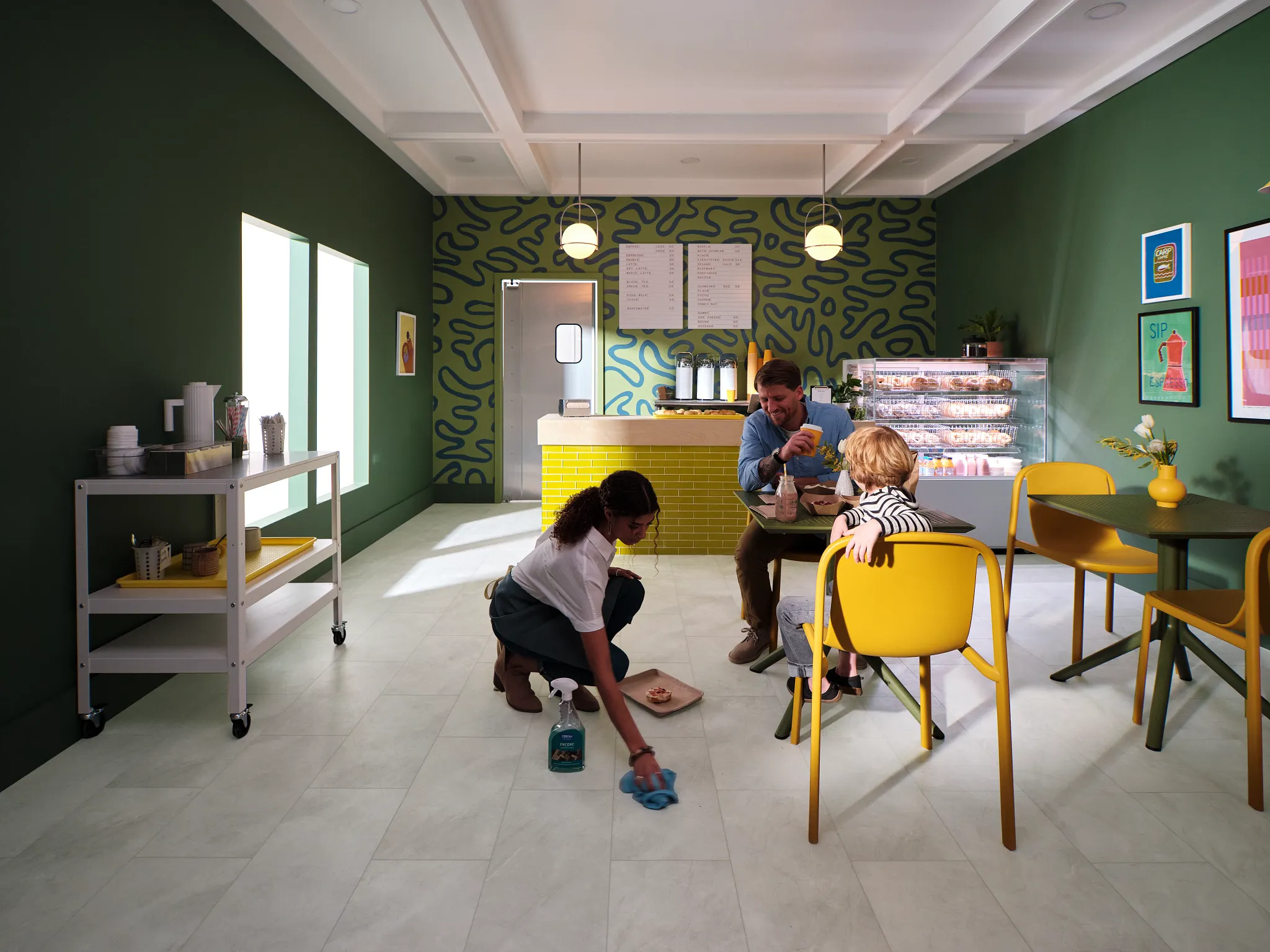 Modern cafe with Coretec Residential SPC luxury vinyl tile flooring in a light stone look, featuring a young woman cleaning the floor and a family dining at a table, 24.02x12.01 inch tiles