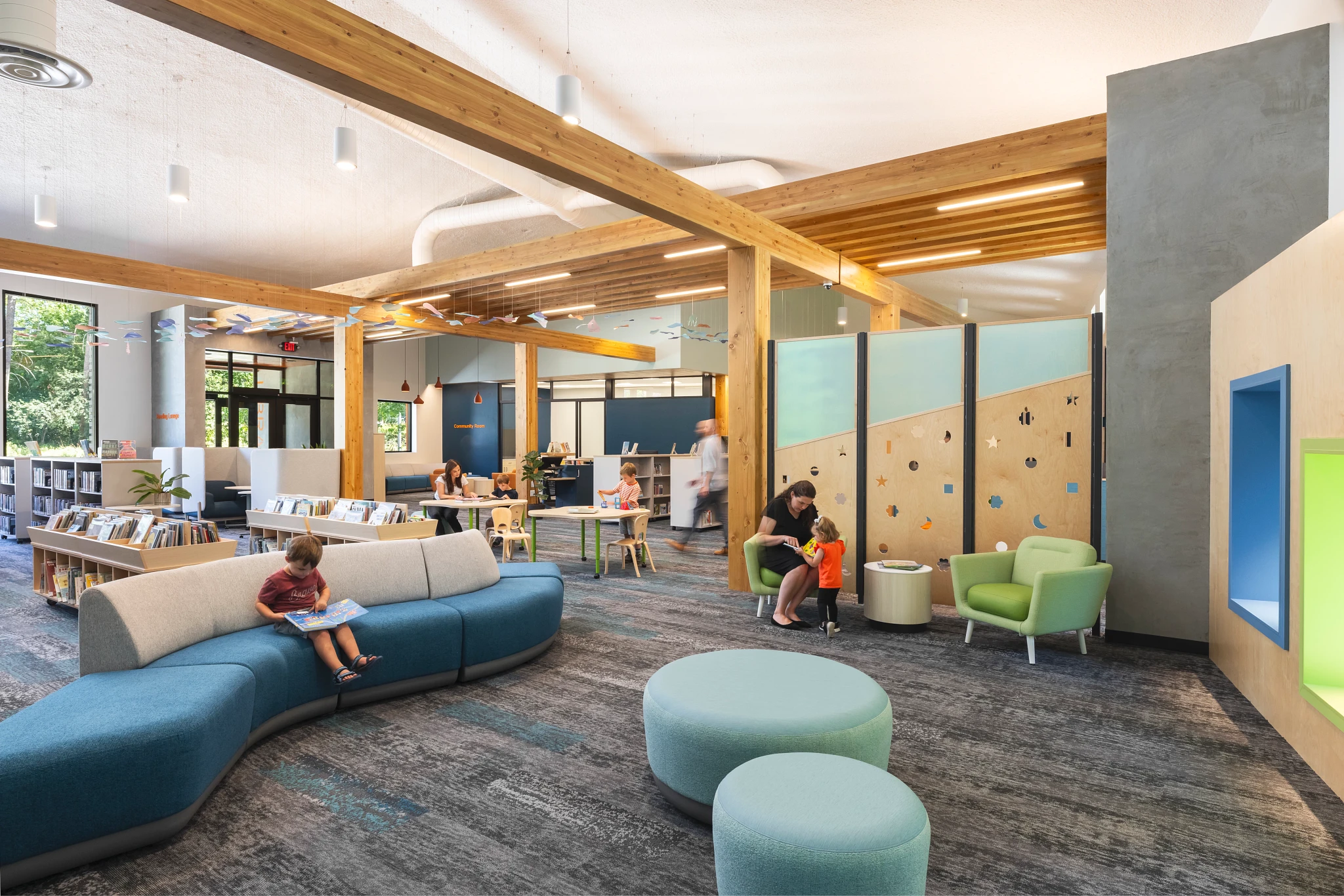 Modern education facility with children and adults in a library setting featuring commercial carpet tile flooring in shades of gray and blue
