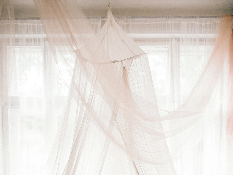 Cozy bedroom scene with white canopy and decorative pillows on a bed